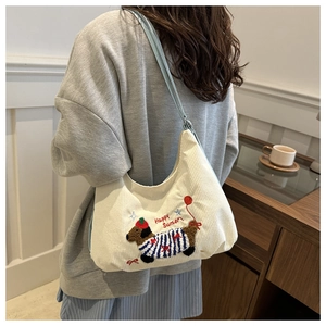 Gros plan du sac cabas en velours côtelé blanc avec broderie chien et détail de la poignée
