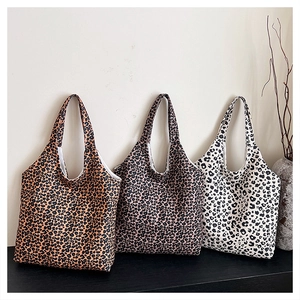 Three leopard print tote bags in brown, purple and white on a minimalist counter display