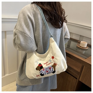 Détail du sac en velours blanc avec teckel brodé et bandoulière en cuir bleu