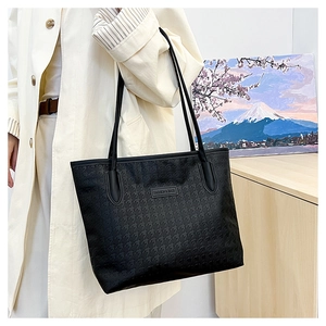 Detail der schwarzen Shopper-Tasche mit Sternprägung und Lederetikett auf einem Mantel