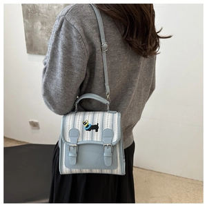 Detail shot of light blue striped backpack with puppy embroidery on model's back