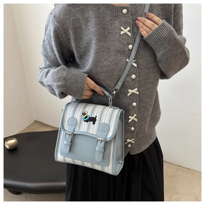 Detail of light blue striped crossbody bag featuring a cute cartoon dog embroidery