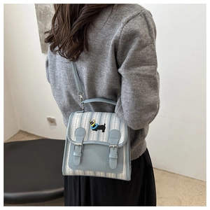 Detail of blue striped canvas backpack with dog embroidery and leather buckle straps