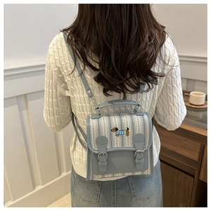 Detail of preppy blue striped backpack with cute dachshund embroidery and leather buckles