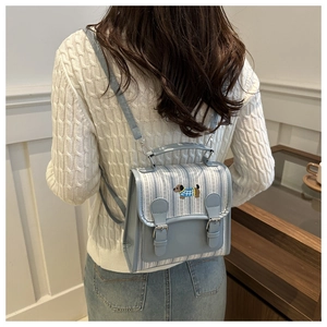 Detail showing embroidered dog motif on light blue striped backpack with buckle closure