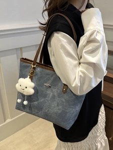 Minimalist denim tote bag with leather trim and cloud charm shown on a model