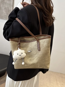 Vintage khaki tote bag with brown leather straps and plush charm on a model