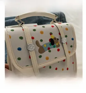 Close-up of embroidered cartoon dog and colorful polka dots on white PU leather bag