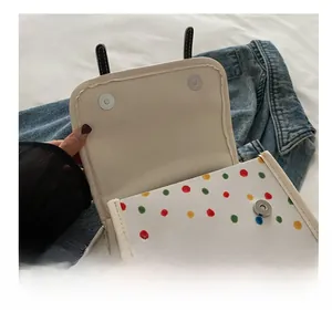 Detail of hardware magnetic snap closure on a polka dot bag with stitching details
