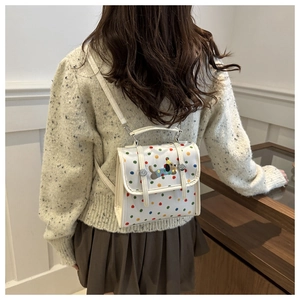 Detail view of colorful polka dot pattern and puppy embroidery on mini PU backpack