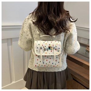 Detail of white mini backpack featuring colorful polka dots and cute dog embroidery
