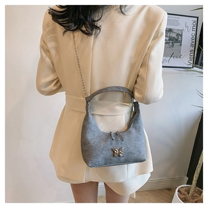 Graue Crescent-Bag mit silbernem Schmetterlingsanhänger und feinem Kettenriemen