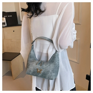 Details der grauen Vintage-Unterarmtasche mit goldener Schmetterlingsschnalle und Kette