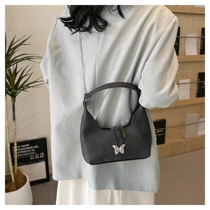 Detail der schwarzen Nylon-Unterachseltasche mit silbernem Schmetterling und Kette