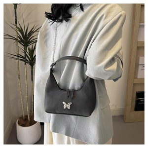 Model trägt eine schwarze Hobo-Bag mit silberner Schmetterlingsschnalle und Kettendetail
