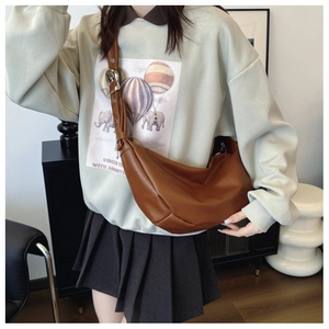 Detail view of a brown leather crescent crossbody bag with adjustable wide shoulder strap