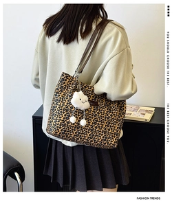 Detail of leopard print tote bag with plush cloud charm and brown leather brand label
