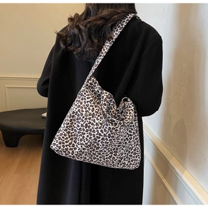 Détail d'un grand sac fourre-tout à imprimé léopard porté sur un manteau noir élégant