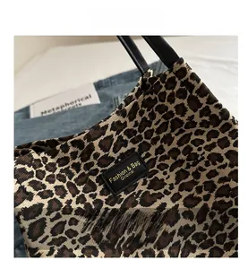 Dettaglio della borsa tote con stampa leopardata e targhetta logo in pelle nera