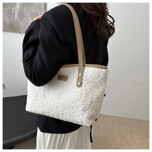 Close-up of white fuzzy shearling tote bag with brown leather handles and detail