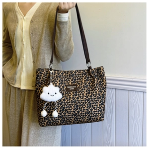 Detail of leopard print tote bag with plush cloud charm and leather logo patch
