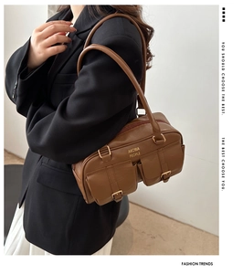 Detail of vintage brown shoulder bag with double pockets and gold buckles on a model