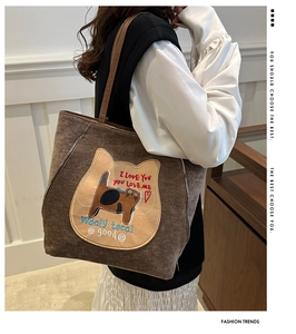 Detail of dark brown tote bag with cat embroidery and slender leather straps