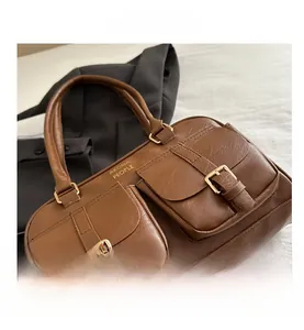 Detailed view of brown leather tote bag with gold buckles and front brand logo
