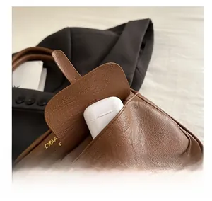 Detail of a brown leather Boston bag showing the external pocket with a headphone case