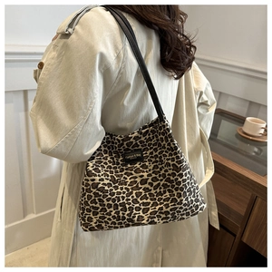 Dettaglio della borsa tote leopardata con cinturini in pelle nera su trench beige