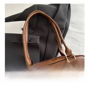 Detail of dark brown leather handbag featuring dual handles and gold metal buckles