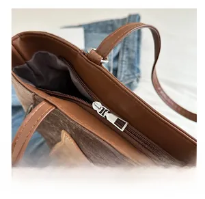Detail view of smooth silver metal zipper and brown leather patchwork on tote bag