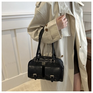 Close-up of black leather handbag featuring dual front pockets and gold hardware