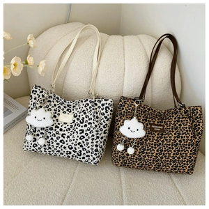 Detail of leopard print canvas tote bags with plush cloud charms on soft fabric