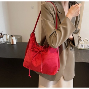Detail einer großen roten Hobo-Tasche aus Wildleder mit eleganter Schleife am Modell