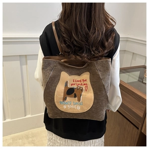 Detail view of large brown tote bag with cat embroidery and side zipper decoration