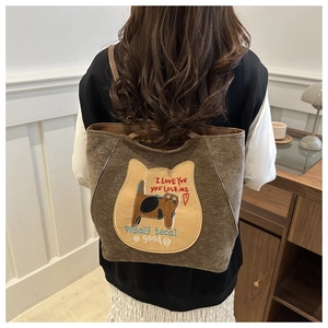 Detail of the cat embroidery and 'I LOVE YOU' text on a brown canvas shoulder bag