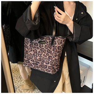 Dettaglio borsa tote leopardata con logo fashion e manici in pelle nera sulla modella