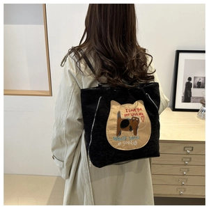Detail of black corduroy tote featuring large cat embroidery and decorative side zippers