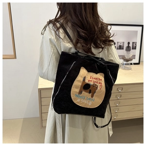 Close-up of black corduroy tote bag with cute cat embroidery and side zipper detail