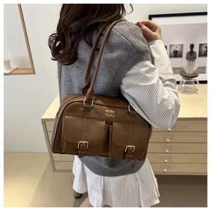 Detail of dark brown leather bowling bag with front pockets and golden logo