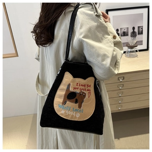 Close-up of black tote bag featuring a cute cat patch with embroidered lettering