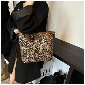 Dettaglio della borsa tote leopardata con manici in pelle marrone e logo in metallo