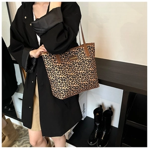 Dettaglio della borsa tote leopardata con manici marroni ed emblema dorato