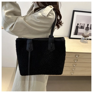 Close-up of black fleece tote bag showing plush texture and durable leather shoulder straps