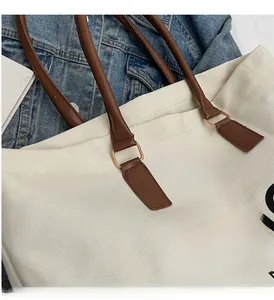 Close-up of premium gold hardware and leather strap on a canvas tote bag