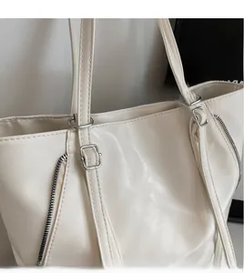 Close-up of cream white PU tote bag with adjustable shoulder strap and silver side zippers