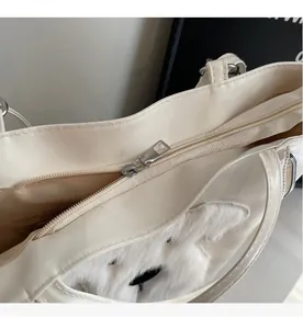 Close-up of smooth silver metal zipper and plush animal detail on beige tote bag