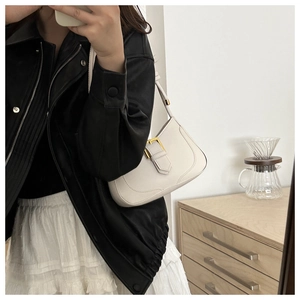 Sac croissant chic blanc cassé avec boucle dorée porté avec une veste en cuir