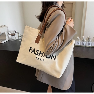 Detail of canvas tote bag with FASHION PARIS print and brown leather shoulder straps